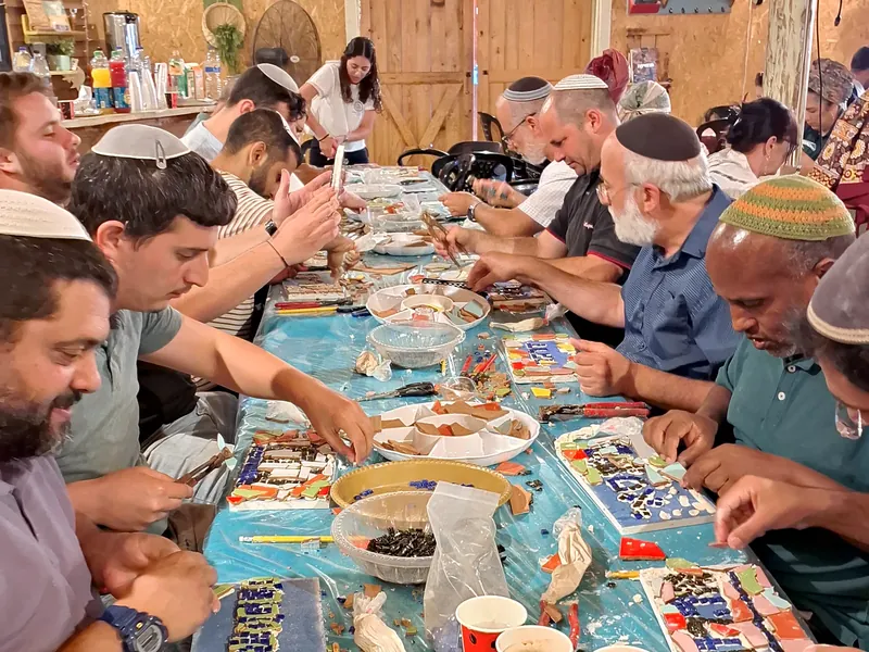 קבוצה סביב שולחן עבודה בזמן סדנת פסיפס